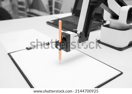 Futuristic robotic arm with pen and blank paper sheet at exhibition Royalty-Free Stock Photo #2144700925