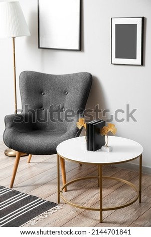 Comfy dark armchair near stylish coffee table