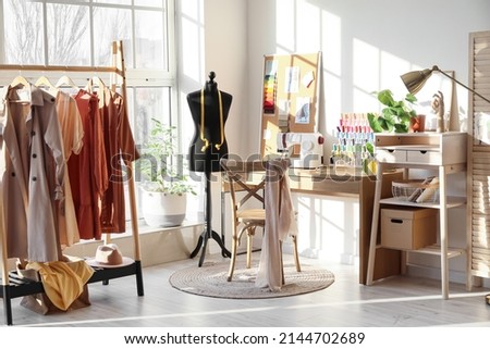 Interior of stylish atelier with tailor's workplace, mannequin and rack Royalty-Free Stock Photo #2144702689