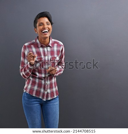 Casual and confident. Studio shot of a beautiful young woman laughing against a grey background.