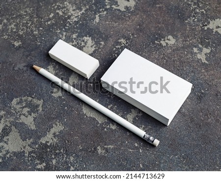 Blank business cards, pencil and eraser on concrete background. Stationery mockup. Objects for placing your design.