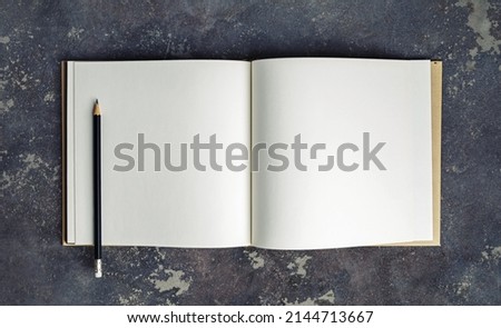 Blank book and pencil mock up on concrete background. Top view.