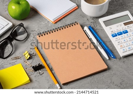 Office desk with notepad, glasses and supplies, close up