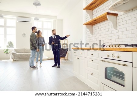 Male relator or broker show home to couple buyers or renters buying fist dwelling together. Man real estate agent demonstrate apartment to tenants. Homeowner, bank loan or mortgage, rent. Royalty-Free Stock Photo #2144715281