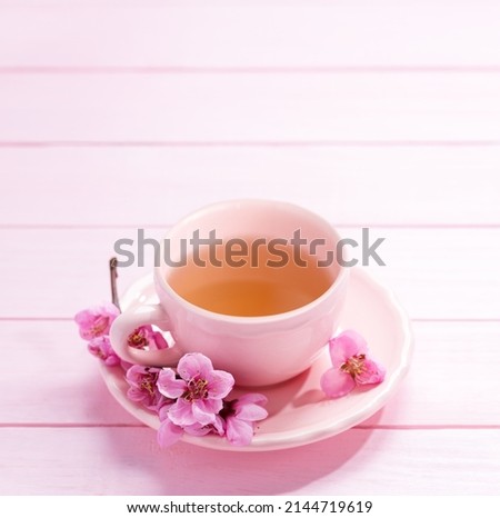 Cup of tea and spring  flowers  (Peach blossom) on light pink wooden table. Selective focus
