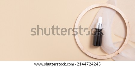Banner with black glass dropper bottle of cosmetics oil or serum top view. Neutral beige monochrome skin care concept. Flat lay.