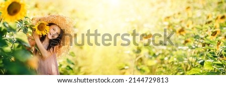 Little happy little girl playing enjoying sunflower flowers on sunny summer day field. Spring and summer background banner. Horizontal photo banner for website header design.