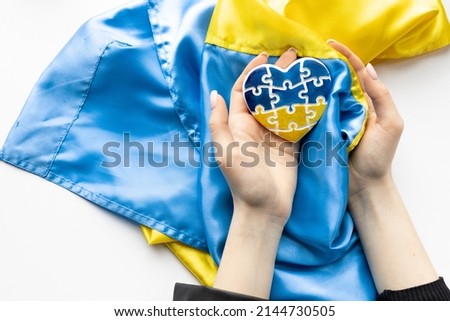 Hand holding Ukraine flag in the shape of heart. Russian-Ukrainian conflict. National security society, prevention of war in Ukraine