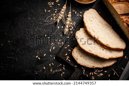 Sliced wheat bread on a cutting board. On a black background. High quality photo