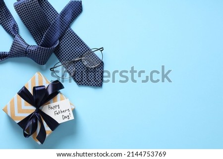Happy Fathers Day background. Flat lay Happy Fathers Day gift box, necktie, glasses on pastel blue table. Royalty-Free Stock Photo #2144753769