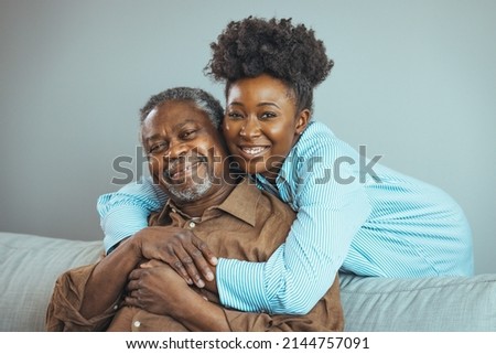 Smiling young woman sitting on sofa with happy older retired 70s father, enjoying pleasant conversation together in living room, mature parents and grown children communication.