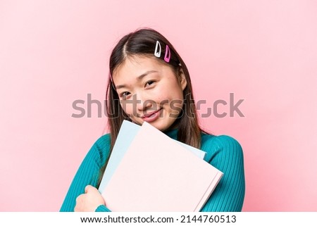 Young asian student woman holding books isolated on pink background