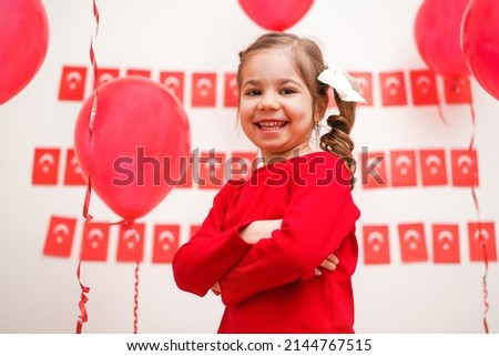 Portrait of small baby girl with Turkish flag. Cute little child celebrating Turkish National Sovereignty and Children's Day or Commemoration of Atatürk Youth and Sports Day. Red white colors concept.
