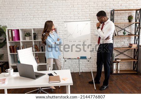Young business man showing a graph to his colleague in a modern office. High quality photo