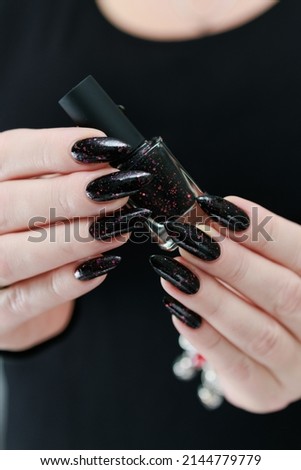 Female hands with long nails and black and red nail polish