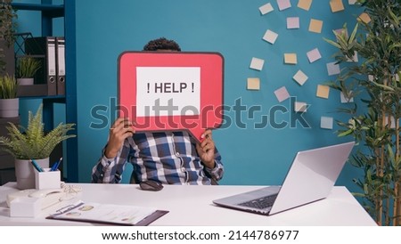 Male employee holding speech bubble with text message to ask for help while he works on laptop to plan business strategy. Project manager showing card board with writing on cartoon mockup.