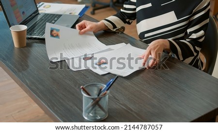 Female HR employee looking at cv resume to hire candidates, analyzing information before job interview. Woman using expertise documents to make job offer and recruit applicants. Close up. Royalty-Free Stock Photo #2144787057