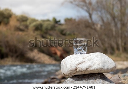 Transparent pure water in glass cup on rock representing the purity of nature