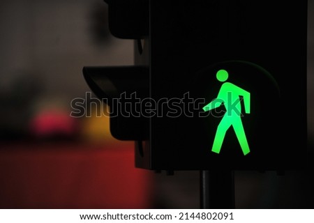 Green traffic light with a walking person symbol in the city street