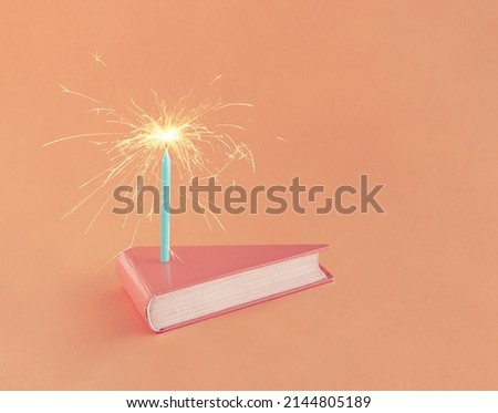 Coral-pink book in the shape of cake slice with sprinkler on isolated pastel background. Minimal abstract creative gift card concept. School or library celebration or anniversary. Happy birthday idea. Royalty-Free Stock Photo #2144805189