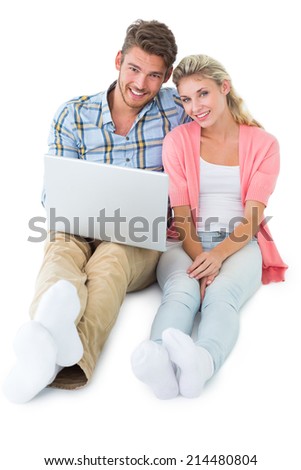 Attractive young couple sitting using laptop on white background