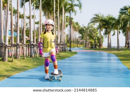 asian child or kid girl playing skateboard or surf skate in skating rink track and extreme sports exercise to wearing helmet elbow pads wrist and knee support for body safety protect at bang phra park Royalty-Free Stock Photo #2144814885