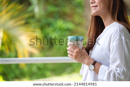 Closeup image of a young woman holding and drinking hot coffee 