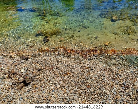 a clear clean pebble beach lake rocks riverbank riverside shoreline shadows hiking trail adventure landscape river water Royalty-Free Stock Photo #2144816229