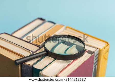 Vintage book and magnifying glass on light blue background. Education background. World books day.