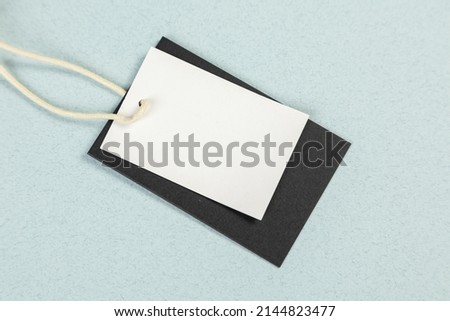 An empty white price tag lies on a gray-blue background with a soft shadow.
