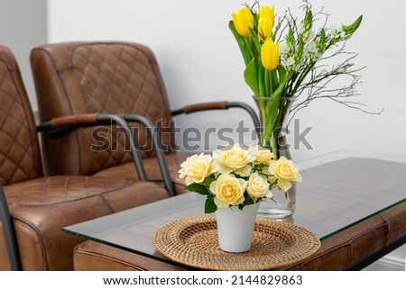 A bouquet of flowers on a table in an interior with leather armchairs.