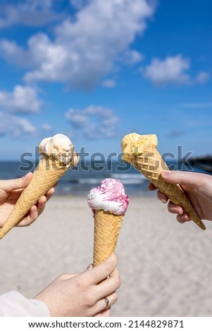 Ice cream in waffle cones in female hands on the background of the sea.