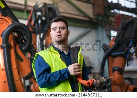 Young man with Down syndrome working in industrial factory, social integration concept. Royalty-Free Stock Photo #2144837111