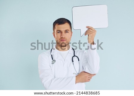 In doctor's uniform. Man standing in the studio with empty signs for the text.