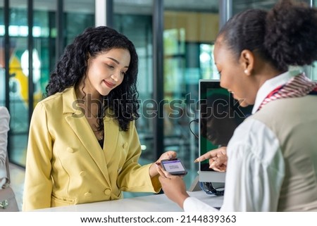 Caucasian passenger show online qr code using mobile phone and passport to airline ground crew at the check-in counter for verification to get boarding pass for airplane travel and transportation  Royalty-Free Stock Photo #2144839363