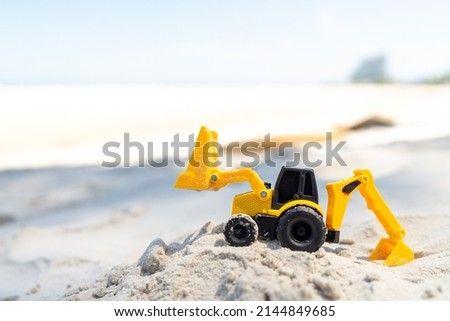 Backhoe toy yellow plastic on beach sand Royalty-Free Stock Photo #2144849685