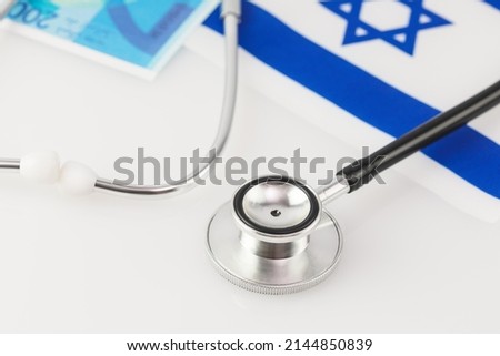 Medical concept. Private medicine in Israel, payment for treatment. Stethoscope, Shekel banknotes and Israel flag on a white background. Soft image and soft focus style Royalty-Free Stock Photo #2144850839