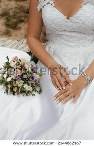 Bride in a stylish white wedding dress. Nearby lies a stylish bouquet of colorful flowers.