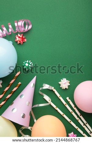 Colorful carnival or party frame of balloons, streamers and confetti on green background. Space for text. Top view