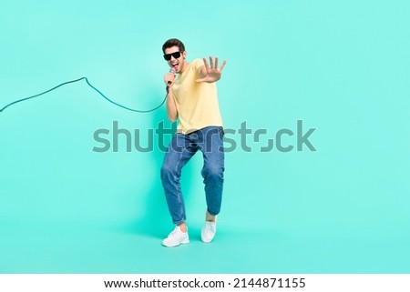 Full size photo of funny brunet young guy sing wear eyewear t-shirt jeans sneakers isolated on teal background Royalty-Free Stock Photo #2144871155