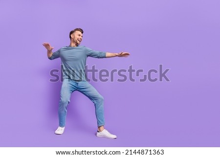 Photo of charming cool guy dressed grey shirt looking empty space dancing riding surf isolated purple color background