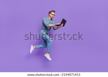 Photo of excited bust guy wear grey shirt spectacles jumping high typing modern device isolated violet color background