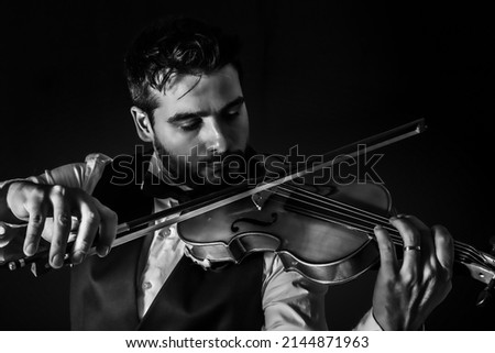 Man playing violin. String musical instrument. Classic music instrument. Elegant man playing classical music with his violin. black and white photo