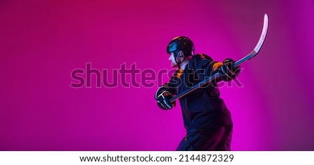 Scoring a goal. Portrait of active man, professional hockey player in motion, training isolated over pink background in neon light. Concept of action, team sport game, energy. Copy space for ad