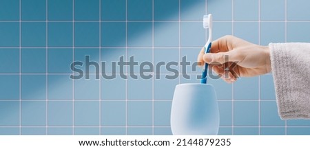 Man cleaning teeth in the bathroom, he is taking his toothbrush in the toothbrush holder Royalty-Free Stock Photo #2144879235