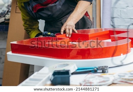 Young worker with a drill in his hand collects an advertising sign