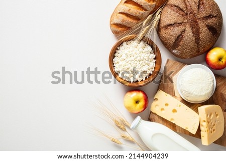 Jewish holiday Shavuot concept with dairy products, fruits, cheese, bread, milk bottle on white table. Flat lay, top view. Royalty-Free Stock Photo #2144904239