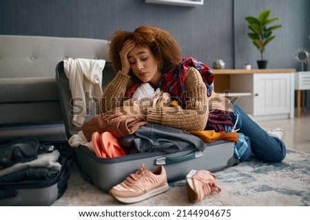 Sad young woman and unpacked vacation luggage Royalty-Free Stock Photo #2144904675
