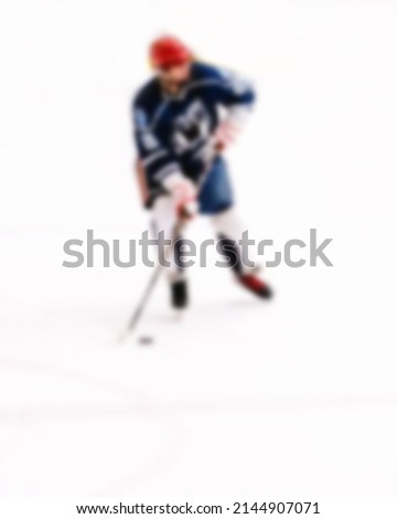 Hockey player silhouette with stick on white ice out of focus - blurred background of ice hockey match - sports background