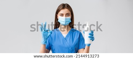 Covid-19, preventing virus, health, healthcare workers and quarantine concept. Confident serious female nurse, pretty doctor in scrubs and medical mask, show hand sanitizer, soap and okay sign